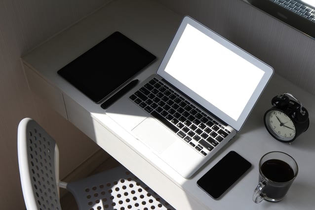 Laptop on desk with coffee, phone, and notepad. 